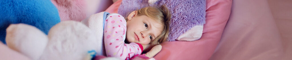 Sie sehen ein Mädchen das im Bett liegt. Sie leidet an niedrigem Blutdruck. Niedriger Blutdruck bei Kindern ist besonders in der Pubertät ein häufiges Phänomen. Viele Heranwachsende leiden in dieser Lebensphase unter Hypotonie, einem Begriff, der sich aus den griechischen Wörtern hypo („unter“) und tónos(„Spannung“) ableitet und wörtlich „Spannungsmangel“ bedeutet. Doch dieser Blutunterdruck im Kindesalter betrifft nicht nur das Gefäßsystem, sondern zeigt sich oft auch auf emotionaler und psychischer Ebene.